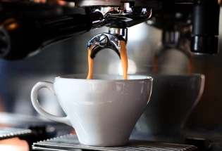 Un café qui coule dans une tasse blanche, servit à la machine à caféaq